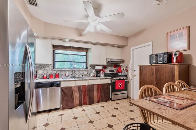 9064 Garland Ave, Surfside, FL 33154 - kitchen featuring stainless steel appliances, under cabinet range hood, light countertops, white cabinets, and tasteful backsplash