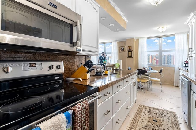 250 174th St Unit 1704, Sunny Isles Beach, FL 33160 - kitchen with stainless steel appliances, white cabinetry, light tile patterned floors, and tasteful backsplash