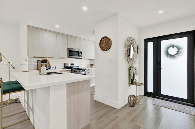 9905 NW 52nd Ln, Doral, FL 33178 - kitchen featuring appliances with stainless steel finishes, light countertops, light wood-type flooring, a peninsula, and modern cabinets