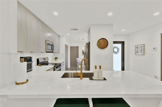 9905 NW 52nd Ln, Doral, FL 33178 - kitchen with stainless steel appliances, light stone counters, modern cabinets, a peninsula, and recessed lighting