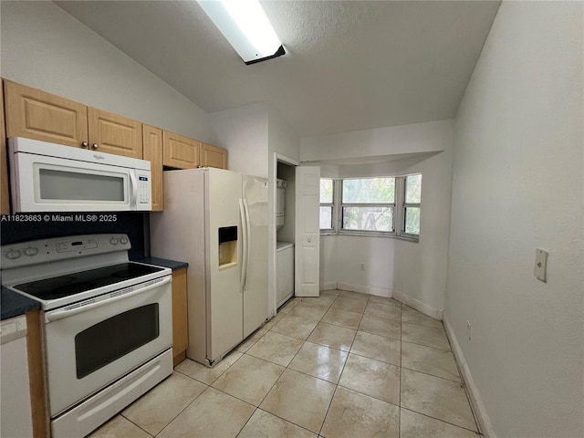 1250 SE 28th Ct Unit 203, Homestead, FL 33035 - kitchen featuring white appliances, light brown cabinetry, dark countertops, stacked washer and clothes dryer, and lofted ceiling