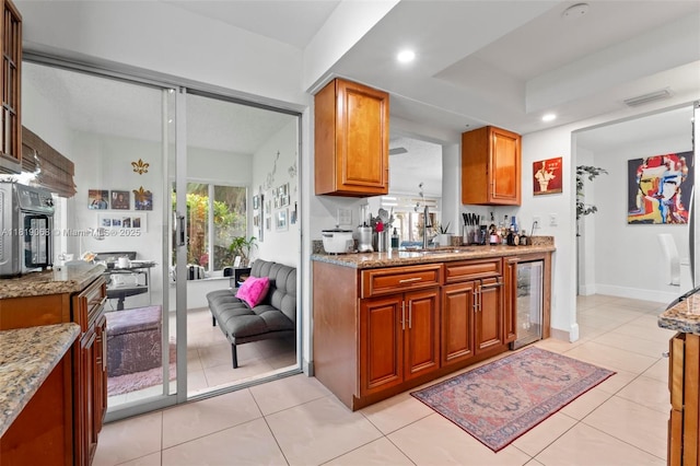 131 NW 31st Ct, Pompano Beach, FL 33064 - kitchen with beverage cooler, brown cabinetry, light stone counters, recessed lighting, and light tile patterned floors