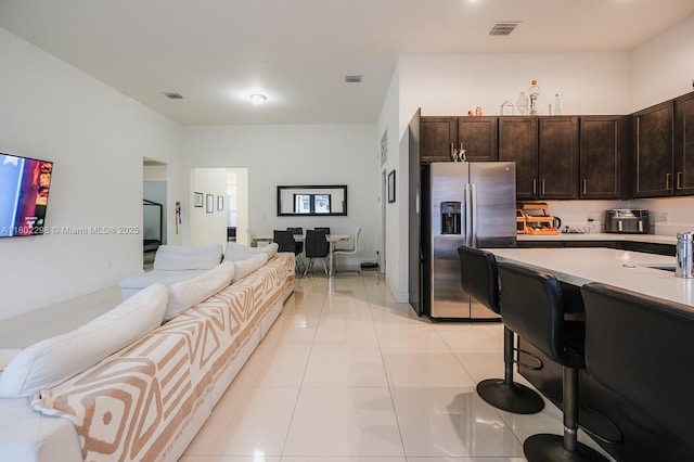 14659 SW 23rd Ter, Miami, FL 33175 - kitchen featuring stainless steel fridge, dark brown cabinets, open floor plan, light countertops, and a breakfast bar area