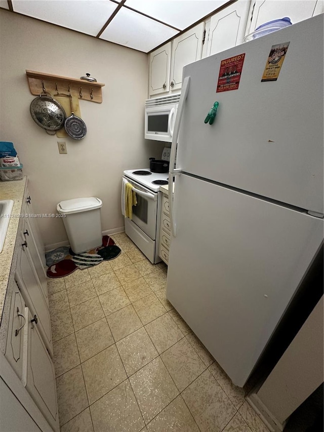 kitchen with white appliances, light countertops, white cabinets, and light tile patterned flooring