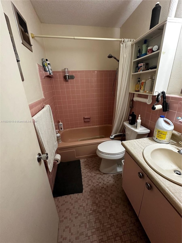full bath with vanity, shower / bathtub combination with curtain, tile patterned floors, tile walls, and a textured ceiling