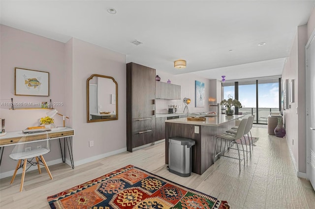 480 NE 31st St Unit 4804, Miami, FL 33137 - kitchen with a breakfast bar area, modern cabinets, a center island, light wood-style floors, and light countertops