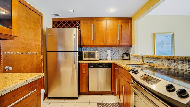 401 Ocean Dr Unit 722, Miami Beach, FL 33139 - kitchen featuring appliances with stainless steel finishes, decorative backsplash, light stone countertops, light tile patterned flooring, and recessed lighting