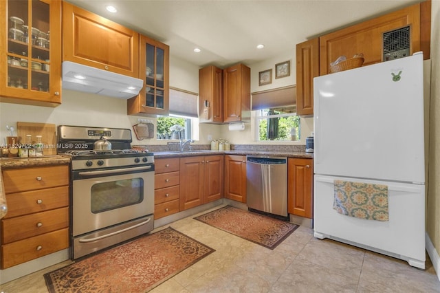 1521 Funston St, Hollywood, FL 33020 - kitchen with appliances with stainless steel finishes, under cabinet range hood, brown cabinets, glass insert cabinets, and recessed lighting