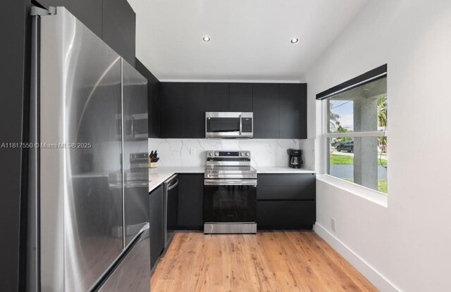 309 SE 3rd Ave, Hallandale Beach, FL 33009 - kitchen featuring appliances with stainless steel finishes, dark cabinetry, light countertops, light wood-style flooring, and recessed lighting