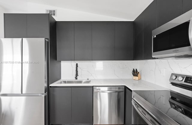 309 SE 3rd Ave, Hallandale Beach, FL 33009 - kitchen featuring stainless steel appliances, modern cabinets, tasteful backsplash, dark cabinetry, and vaulted ceiling