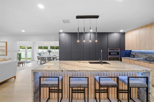 11530 NE 7th Ave, Biscayne Park, FL 33161 - kitchen featuring modern cabinets, a kitchen breakfast bar, double oven, light stone counters, and hanging light fixtures