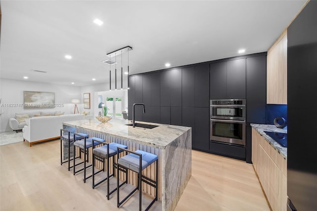 11530 NE 7th Ave, Biscayne Park, FL 33161 - kitchen featuring modern cabinets, double oven, a breakfast bar area, light wood finished floors, and a spacious island