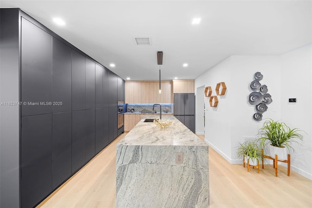 11530 NE 7th Ave, Biscayne Park, FL 33161 - kitchen featuring modern cabinets, freestanding refrigerator, light wood-type flooring, an island with sink, and recessed lighting