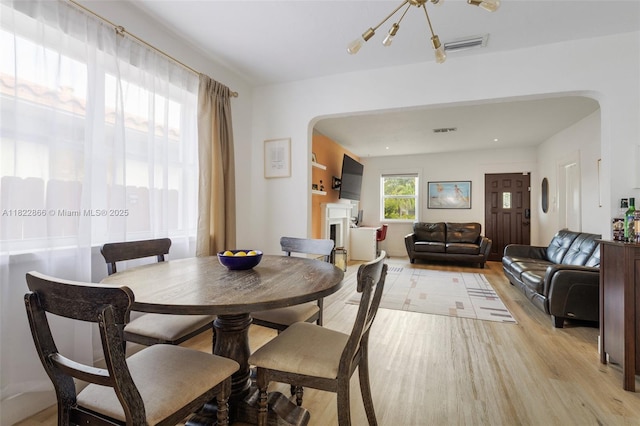 3422 SW 25th St, Miami, FL 33133 - dining area featuring light wood finished floors, a fireplace, and arched walkways