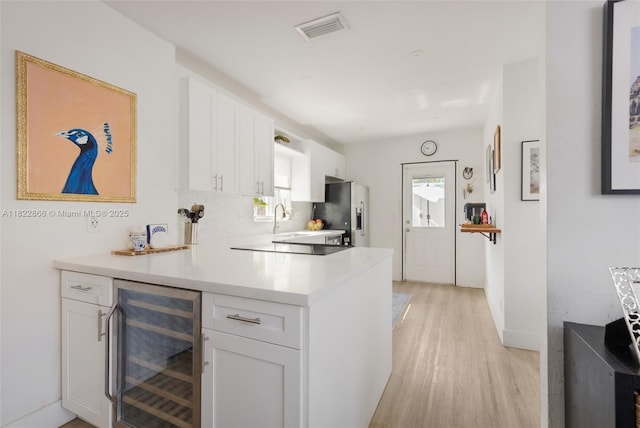 3422 SW 25th St, Miami, FL 33133 - kitchen with wine cooler, stainless steel fridge with ice dispenser, light wood-type flooring, white cabinets, and light countertops