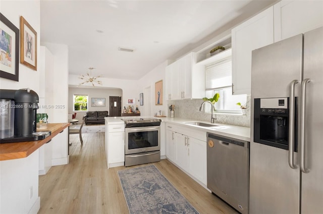 3422 SW 25th St, Miami, FL 33133 - kitchen featuring stainless steel appliances, white cabinets, open floor plan, and light wood-type flooring