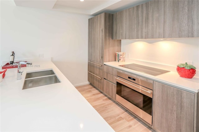 801 S Miami Ave Unit 3108, Miami, FL 33130 - kitchen featuring oven, modern cabinets, black electric stovetop, light countertops, and light wood-type flooring