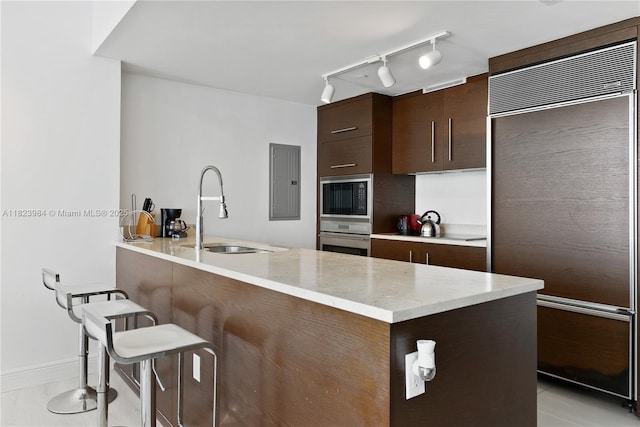 465 Brickell Ave Unit 2003, Miami, FL 33131 - kitchen with built in appliances, dark brown cabinetry, a peninsula, a kitchen bar, and electric panel