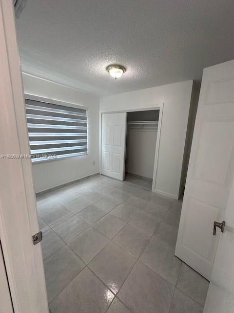 641 SW 99th Pl, Miami, FL 33174 - unfurnished bedroom with light tile patterned floors, a textured ceiling, and a closet