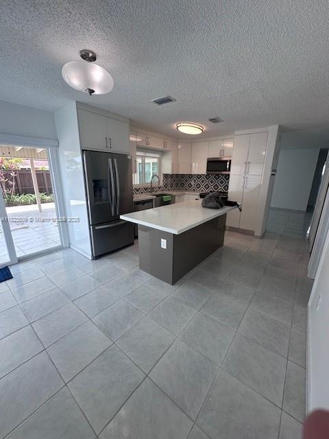 641 SW 99th Pl, Miami, FL 33174 - kitchen with fridge with ice dispenser, stainless steel microwave, light countertops, a kitchen island, and tasteful backsplash