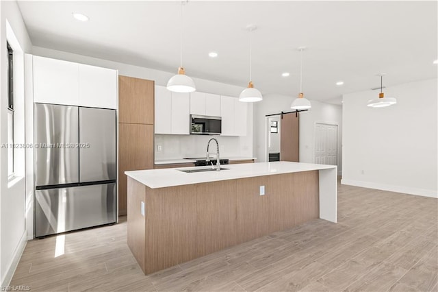 3305 18th St W, Lehigh Acres, FL 33971 - kitchen featuring stainless steel appliances, a center island with sink, a barn door, white cabinetry, and light countertops