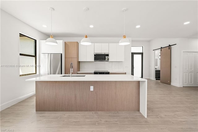 3305 18th St W, Lehigh Acres, FL 33971 - kitchen with stainless steel appliances, white cabinets, a large island with sink, a barn door, and light countertops