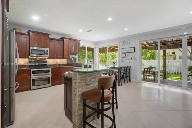 801 NW 156th Ave, Pembroke Pines, FL 33028 - kitchen featuring stainless steel appliances, decorative backsplash, light tile patterned flooring, a kitchen breakfast bar, and recessed lighting