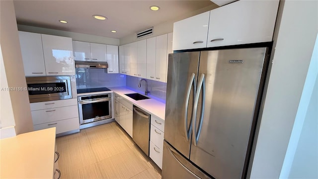 900 Bay Dr Unit 906, Miami Beach, FL 33141 - kitchen with stainless steel appliances, under cabinet range hood, white cabinetry, light countertops, and recessed lighting