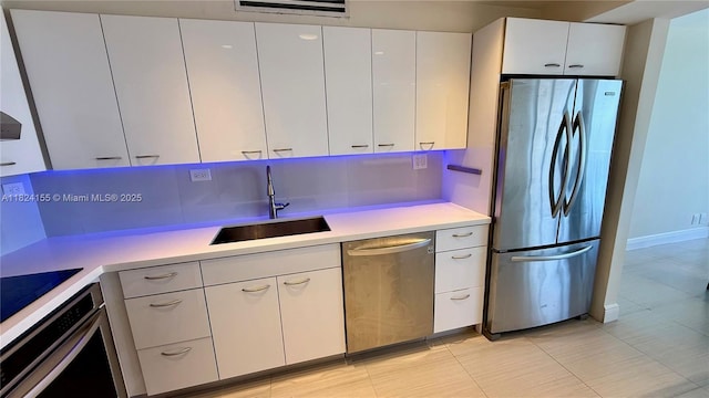 900 Bay Dr Unit 906, Miami Beach, FL 33141 - kitchen with stainless steel appliances, light countertops, white cabinets, and light tile patterned floors