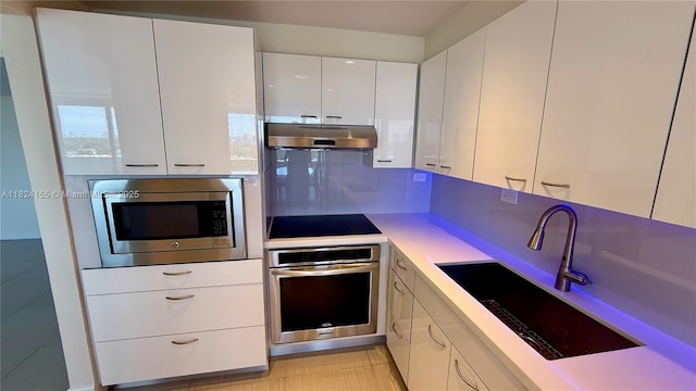 900 Bay Dr Unit 906, Miami Beach, FL 33141 - kitchen featuring appliances with stainless steel finishes, under cabinet range hood, white cabinetry, light countertops, and modern cabinets