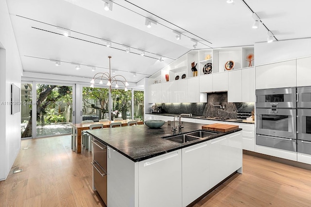 11 La Gorce Cir, Miami Beach, FL 33141 - kitchen featuring track lighting, a warming drawer, dark countertops, a kitchen island with sink, and light wood-style floors