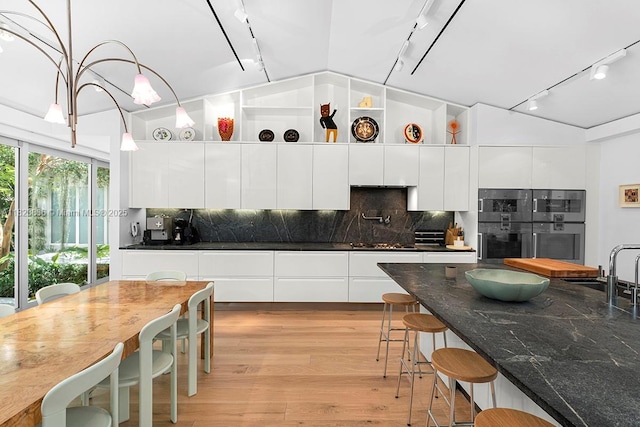 11 La Gorce Cir, Miami Beach, FL 33141 - kitchen with rail lighting, modern cabinets, vaulted ceiling, white cabinetry, and a breakfast bar area