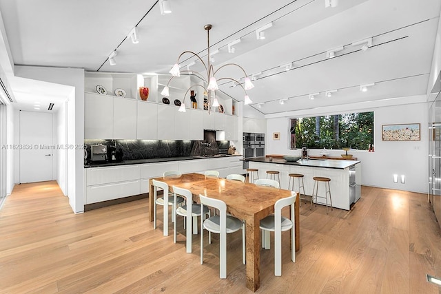 11 La Gorce Cir, Miami Beach, FL 33141 - dining area featuring rail lighting, light wood finished floors, and vaulted ceiling