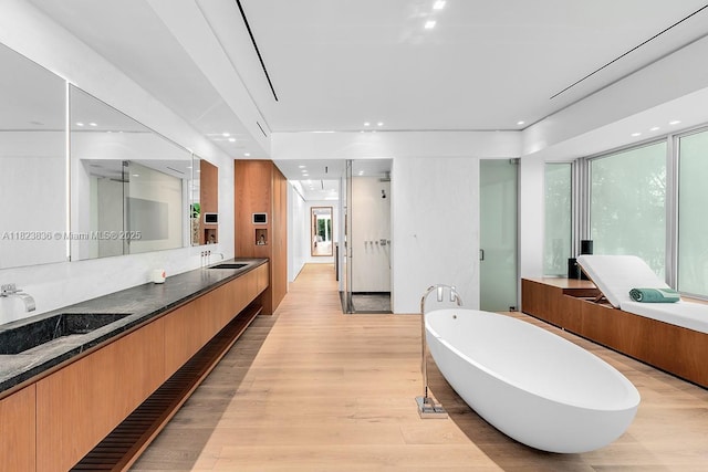 11 La Gorce Cir, Miami Beach, FL 33141 - full bathroom with a freestanding bath, double vanity, wood finished floors, plenty of natural light, and recessed lighting