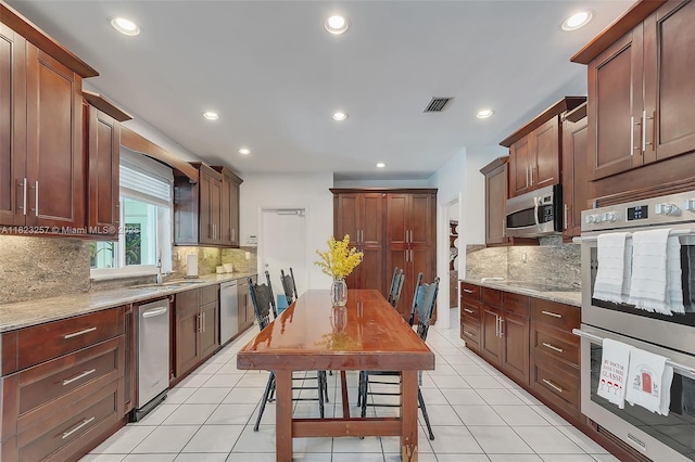 7340 SW 123rd Ter, Pinecrest, FL 33156 - kitchen with appliances with stainless steel finishes, decorative backsplash, recessed lighting, light tile patterned floors, and light stone counters