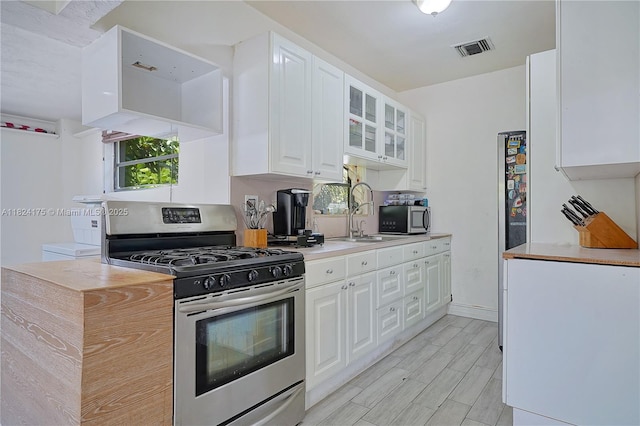 1395 NE 178th St, North Miami Beach, FL 33162 - kitchen featuring stainless steel appliances, white cabinetry, glass insert cabinets, and light countertops
