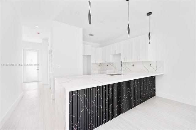 10741 SW 217th St, Miami, FL 33170 - kitchen featuring light stone countertops, a peninsula, white cabinets, decorative backsplash, and hanging light fixtures