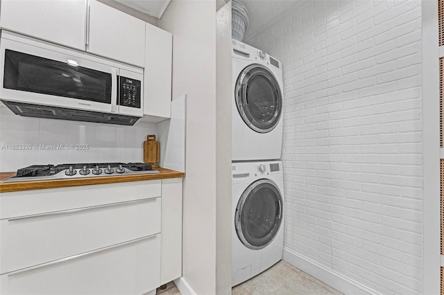 10371 SW 146th St, Miami, FL 33176 - laundry area with stacked washing machine and dryer, brick wall, and light tile patterned flooring