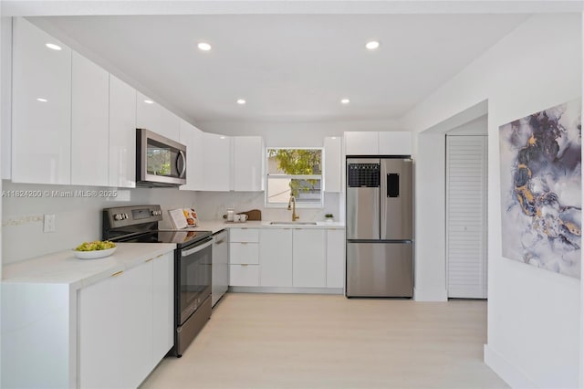 813SW 3rd Ct, Delray Beach, FL 33444 - kitchen with stainless steel appliances, modern cabinets, light wood-style flooring, white cabinetry, and recessed lighting