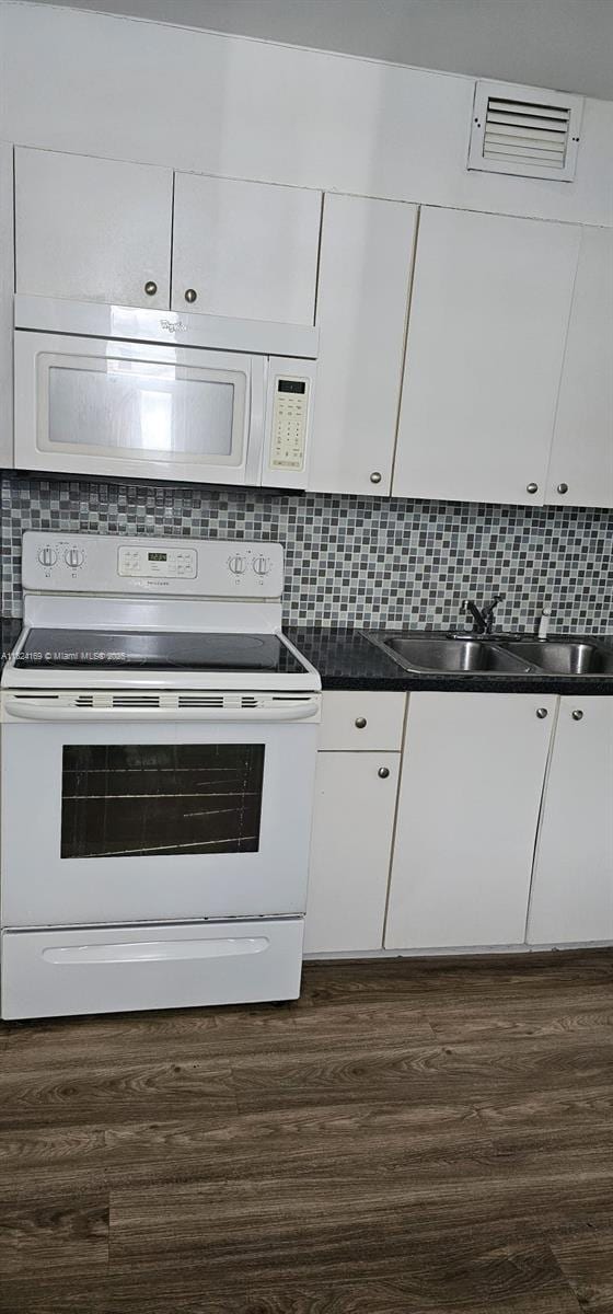 3660 NE 166th St Unit 503, North Miami Beach, FL 33160 - kitchen with white appliances, white cabinets, dark wood-style floors, and decorative backsplash