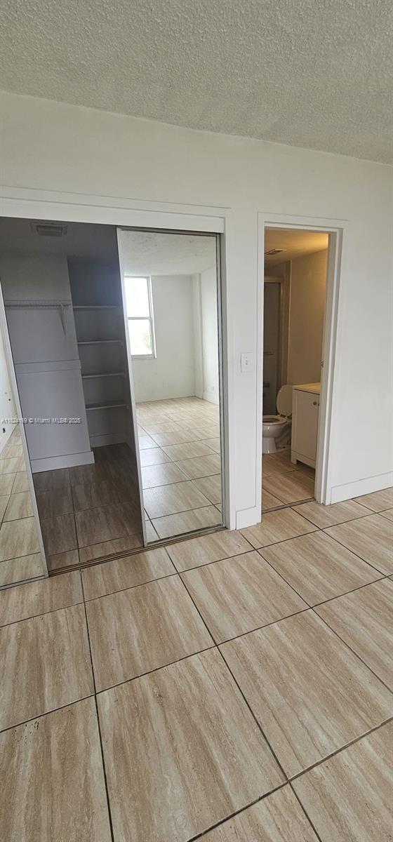3660 NE 166th St Unit 503, North Miami Beach, FL 33160 - unfurnished bedroom featuring tile patterned floors, a textured ceiling, and a closet