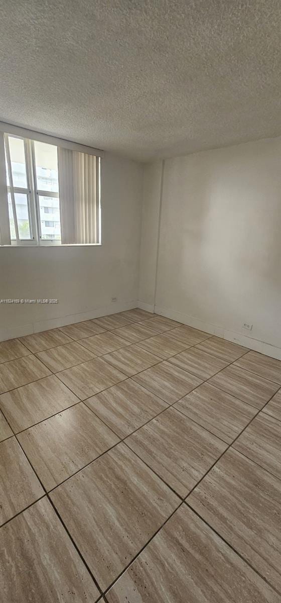 3660 NE 166th St Unit 503, North Miami Beach, FL 33160 - tiled empty room with a textured ceiling