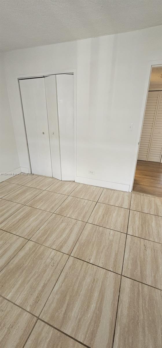3660 NE 166th St Unit 503, North Miami Beach, FL 33160 - unfurnished bedroom featuring a closet and tile patterned flooring