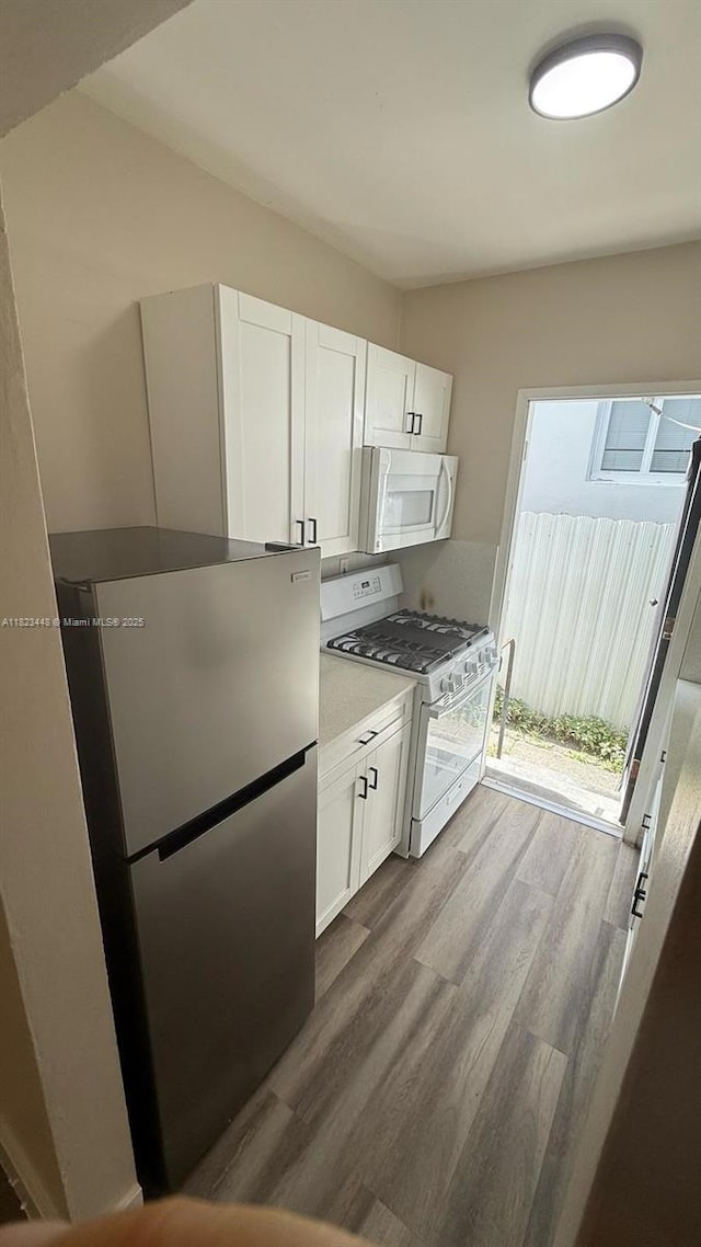 8132 Harding Ave Unit 2, Miami Beach, FL 33141 - kitchen with white appliances, dark wood-type flooring, white cabinets, and light countertops