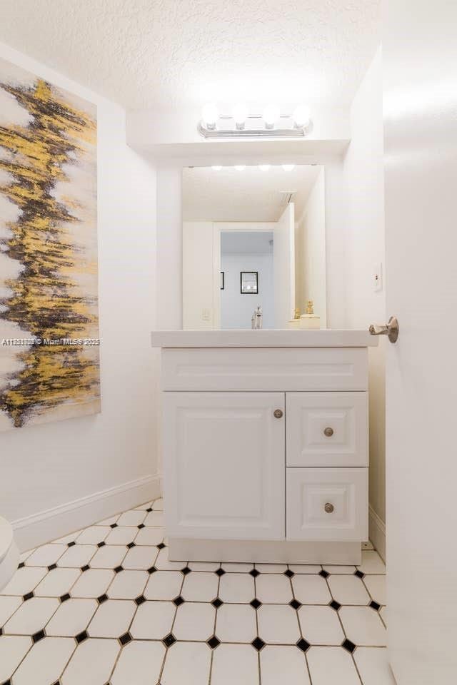 203 SE 8th St, Dania Beach, FL 33004 - half bath with vanity, tile patterned floors, and a textured ceiling