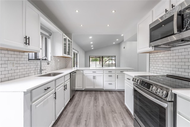 272 Fairway Cir Unit 98, Weston, FL 33326 - kitchen featuring appliances with stainless steel finishes, lofted ceiling, a peninsula, light wood-style flooring, and light countertops
