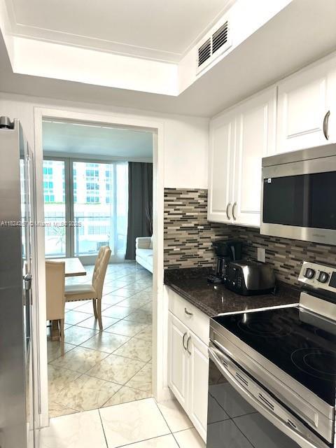 3505 S Ocean Dr Unit 419, Hollywood, FL 33019 - kitchen featuring appliances with stainless steel finishes, tasteful backsplash, white cabinets, and light marble finish flooring