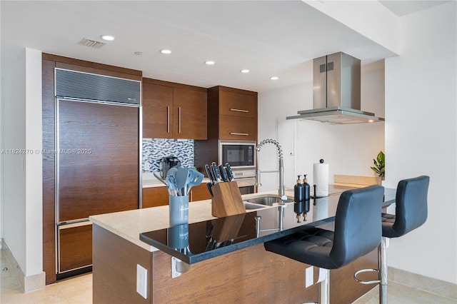 495 Brickell Unit 5705, Miami, FL 33131 - kitchen featuring built in appliances, exhaust hood, a breakfast bar area, recessed lighting, and light tile patterned floors