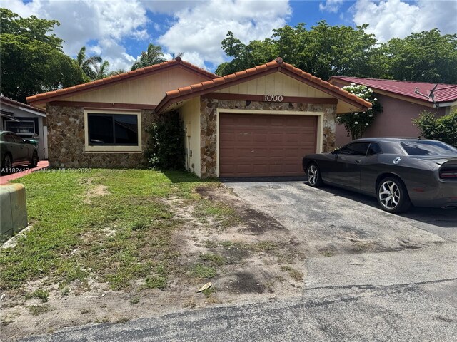 1000 SW 136th Pl, Miami, FL 33184 - ranch-style home with stone siding, an attached garage, asphalt driveway, a front yard, and a tile roof