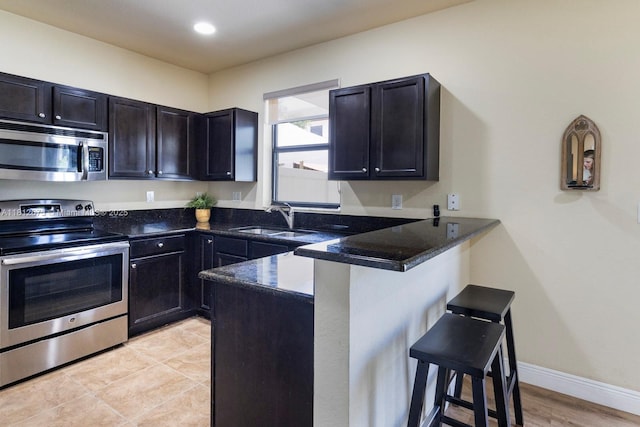 3324 W 90, Hialeah, FL 33018 - kitchen featuring stainless steel appliances, a breakfast bar area, a peninsula, dark stone counters, and recessed lighting